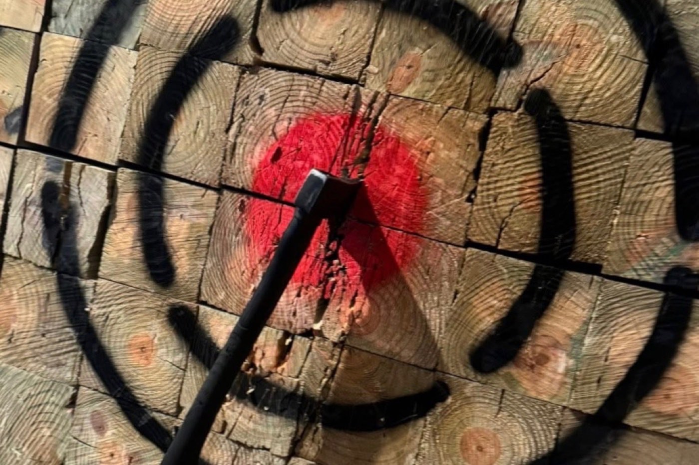 An axe stuck in the red centre of a chewed-up wooden target at The Axe House